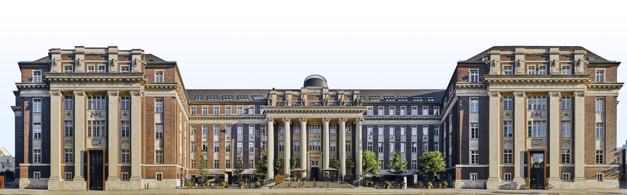 Panoramic photograph of the historic façade of the luxury hotel The Wellem in Düsseldorf with monumental columns, symmetrical architecture and classicist details in clear daylight.