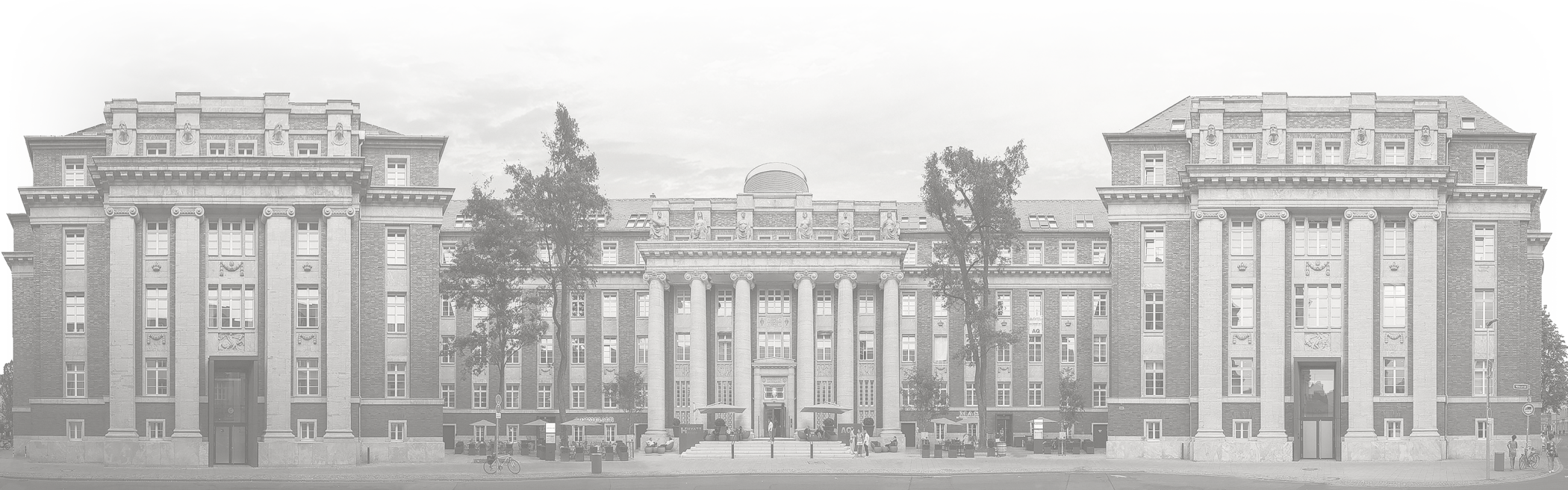 Panoramic photograph of the historic façade of the luxury hotel The Wellem in Düsseldorf with monumental columns, symmetrical architecture and classicist details in clear daylight.