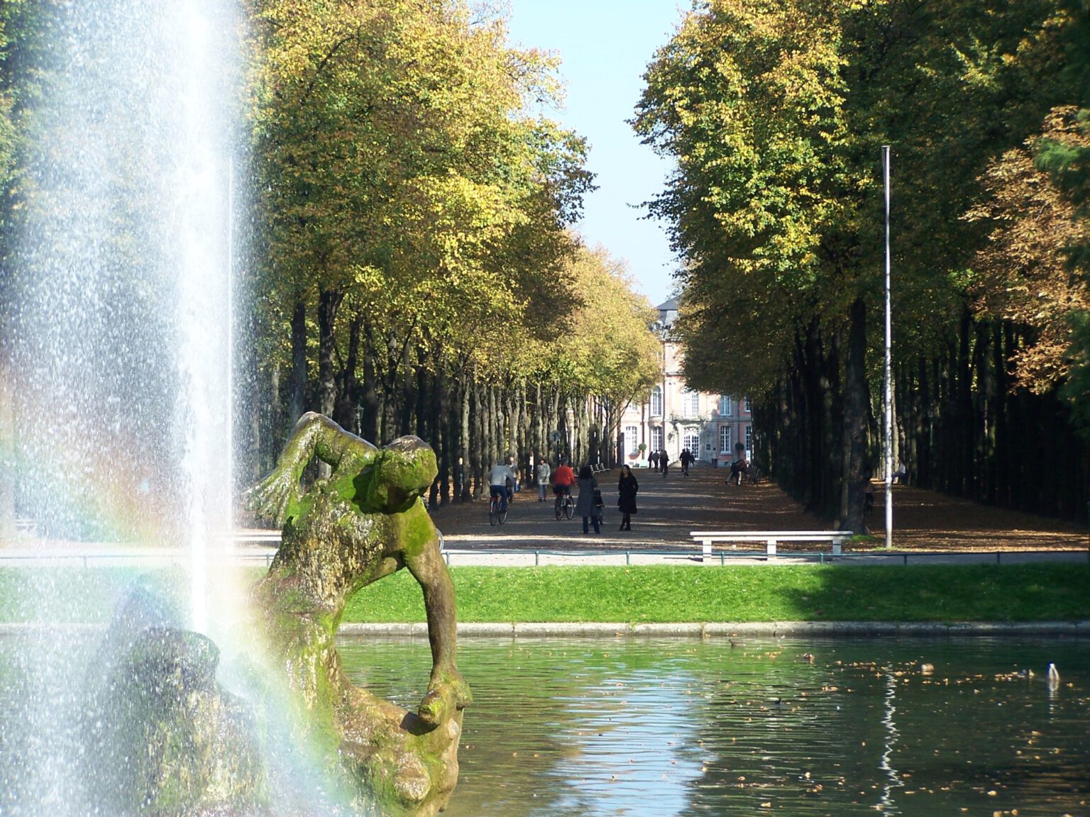 Fountain and historic avenue of trees in Düsseldorf's Hofgarten with a view towards Jägerhof near Hotel The Wellem