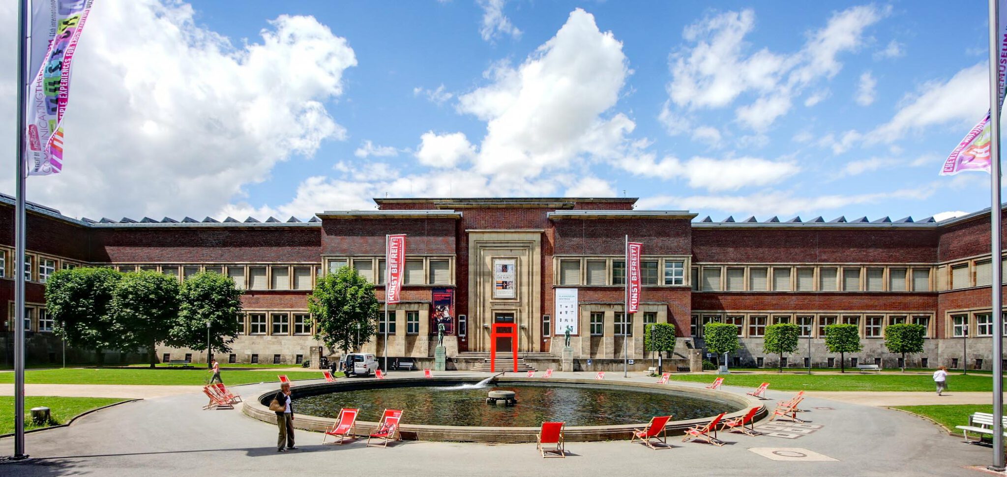 Exterior view of the Kunstpalast in Düsseldorf with fountain, deckchairs and spacious forecourt in sunny weather near The Wellem Hotel
