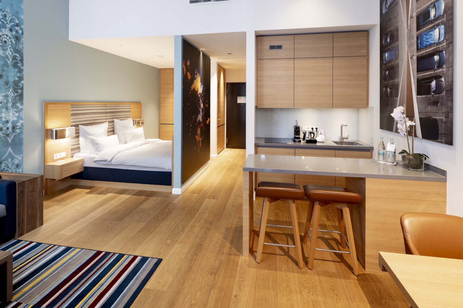 Business suite at Hotel The Wellem Düsseldorf with modern living and sleeping area, open kitchen block, high-quality wooden interior and elegant design.