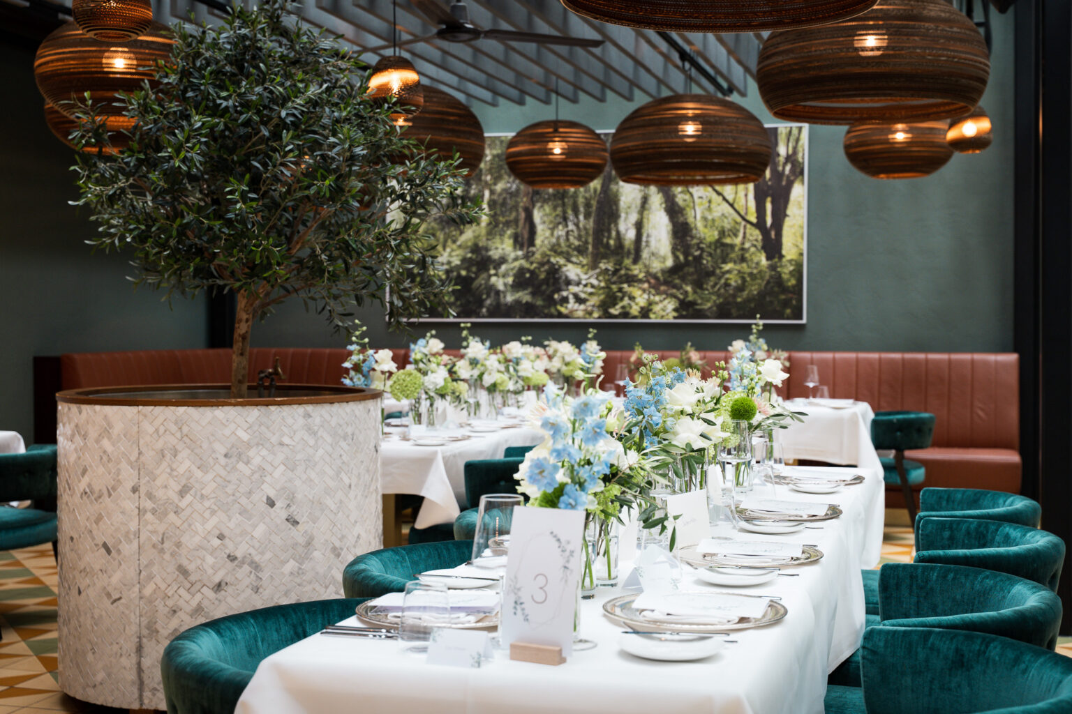 Festively laid table with floral decorations in the Pitti - Cucina Italiana restaurant at The Wellem Hotel Düsseldorf in front of an elegant interior and large hanging lamps