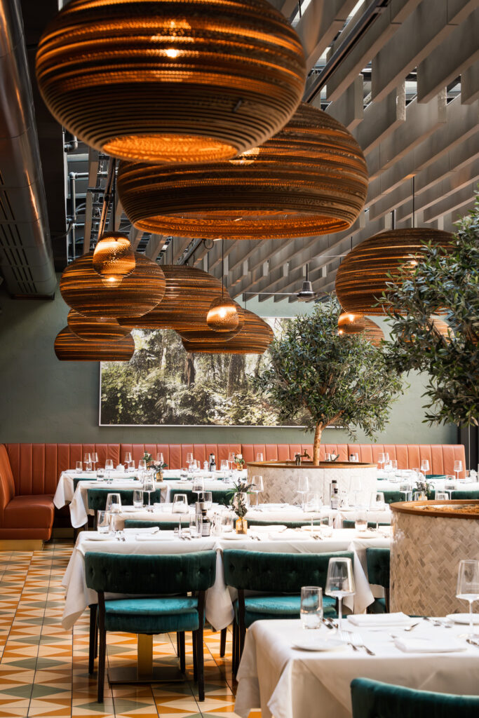 Stylishly decorated interior of the Pitti - Cucina Italiana restaurant at The Wellem Hotel Düsseldorf with large, warm pendant lights, olive trees and elegant interiors